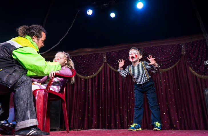 A child dressed as a clown onstage