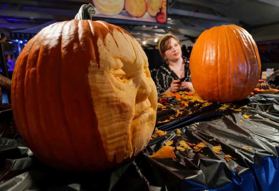 Pumpkin carving artist Carli Ihde, works on a new creation as a seemingly grumpy pumpkin greets visitors to Windigo Fest in 2022. This year's festival will run Oct. 6 to 8.