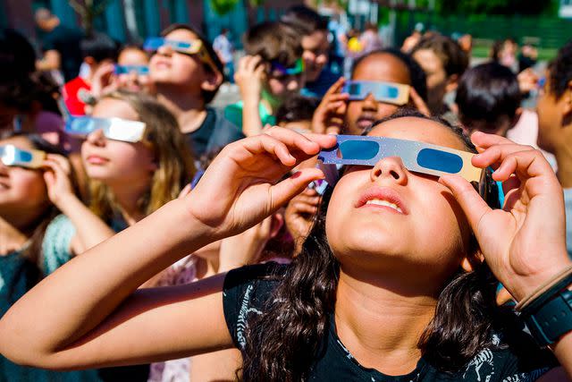 <p>MARCO DE SWART/ANP/AFP via Getty</p> Pupils, wearing protective glasses, look at the partial solar eclipse in Schiedam on June 10, 2021