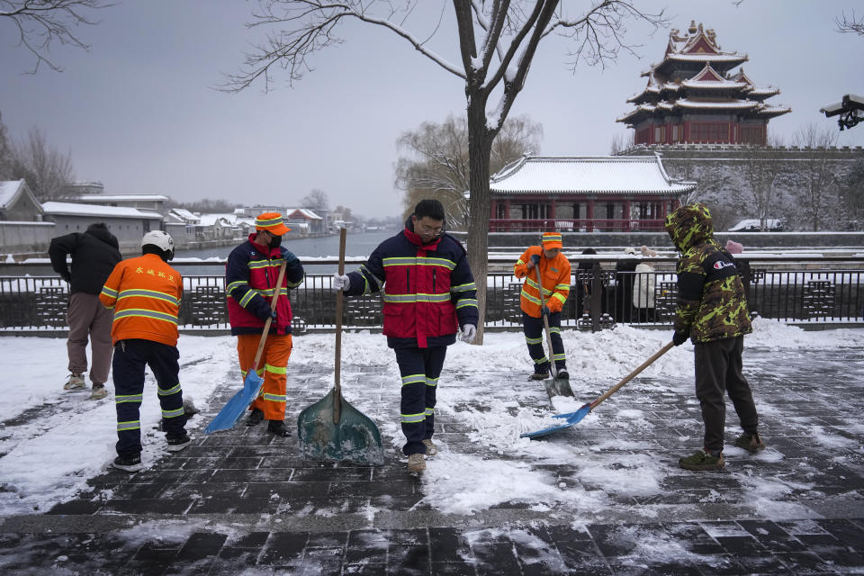 City workers clear the snow on a pathway near the Forbidden City after a snow fall in Beijing, Monday, Dec. 11, 2023. An overnight snowfall across much of northern China prompted road closures and the suspension of classes and train service on Monday.(AP Photo/Andy Wong)