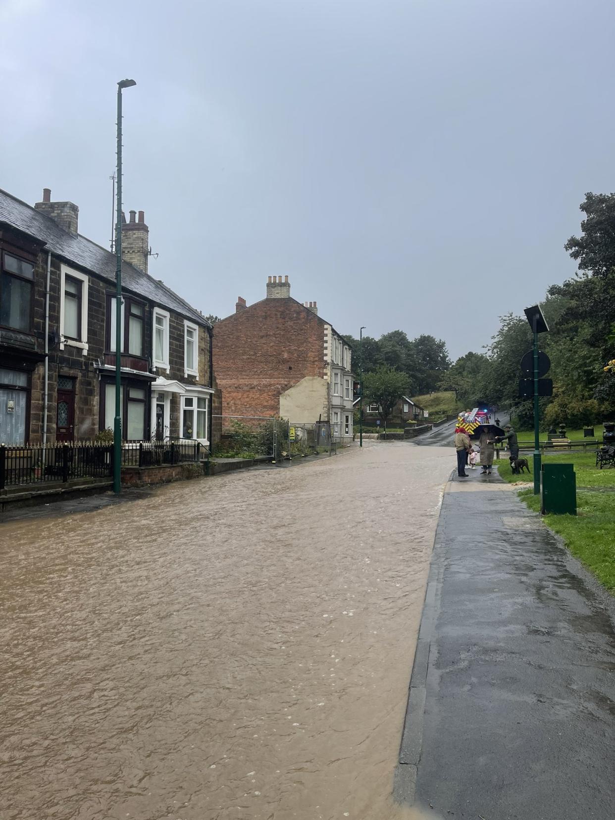 A view of the street with houses on one side as the road is full of water