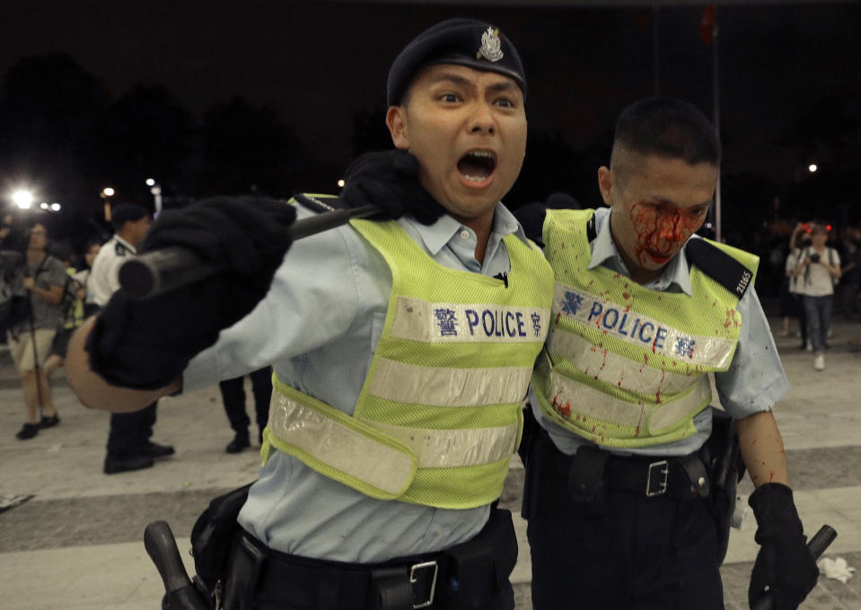 A Hong Kong police officer with blood flowing down his face is assisted by his colleague after clashing with protesters in a rally against the proposed amendments to the extradition law at the Legislative Council in Hong Kong during the early hours of Monday, June 10, 2019. The extradition law has aroused concerns that this legislation would undermine the city's independent judicial system as it allows Hong Kong to hand over fugitives to the jurisdictions that the city doesn't currently have an extradition agreement with, including mainland China, where a fair trial might not be guaranteed. (AP Photo/Vincent Yu)