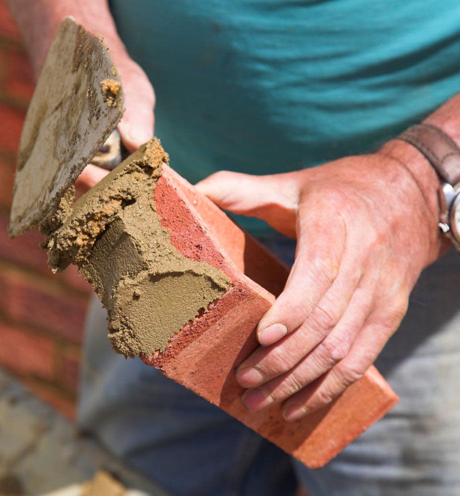 A bricklayer laying a brick.