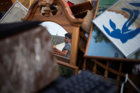 Isaac Zermeno is reflected in a mirror as he helps discard furniture from the house of a neighbor who was left flooded from Tropical Storm Harvey in Houston, Texas, U.S. September 3, 2017. REUTERS/Adrees Latif