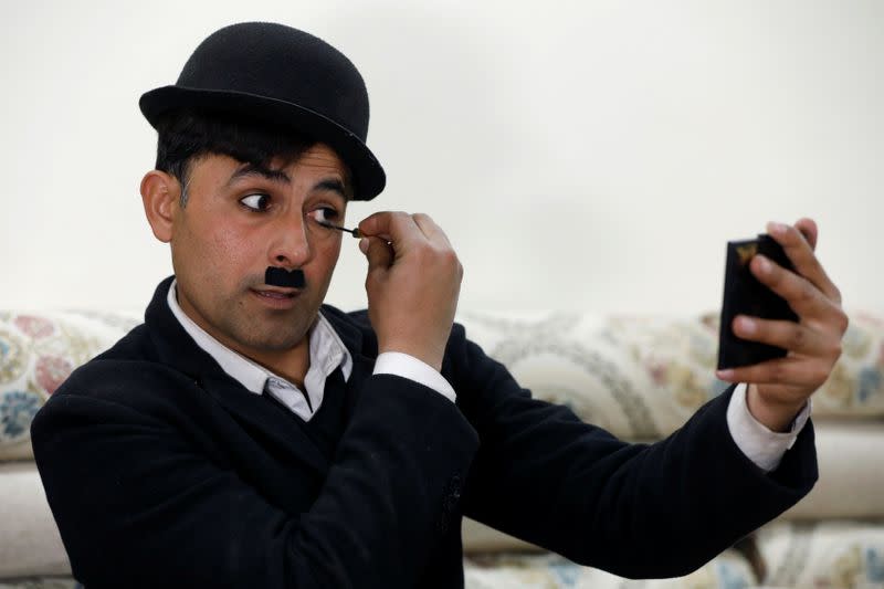 Usman Khan, 29, dressed up as Charlie Chaplin, looks into mirror as he applies mascara in Peshawar