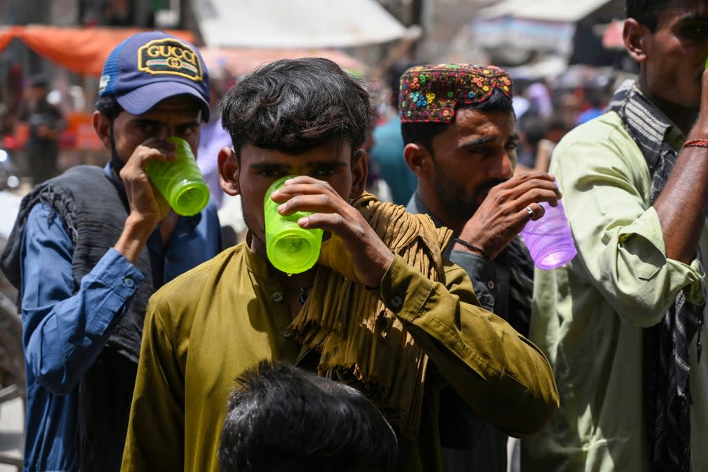 People drink water being distributed by volunteers along a street during a heatwave in Jacobabad, in the southern Sindh province of Pakistan (AFP via Getty Images)