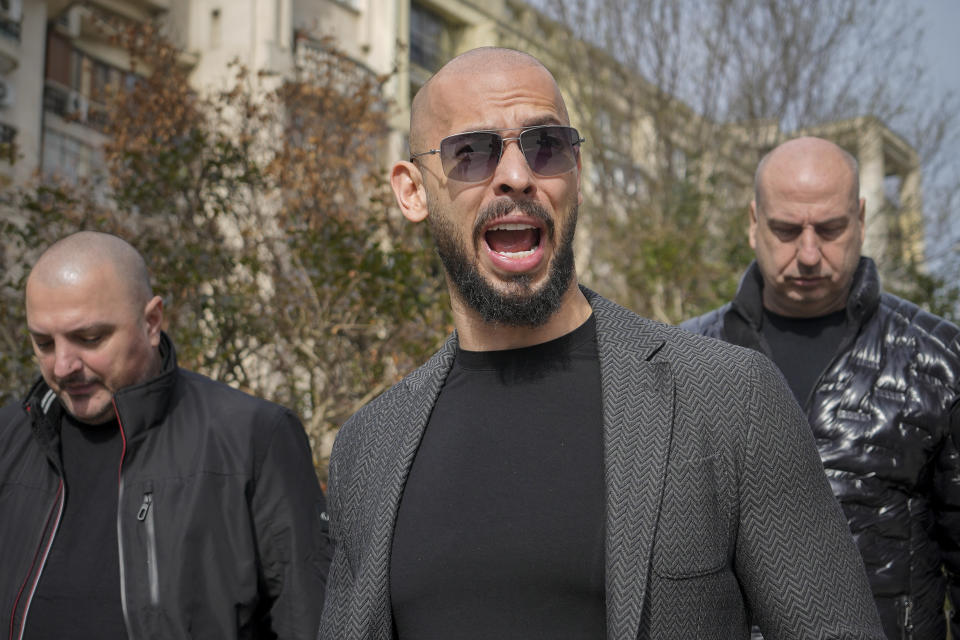 FILE - Andrew Tate grimaces as he arrives at the Bucharest Tribunal in Bucharest, Romania, Monday, Feb. 26, 2024. A court in Romania's capital on Friday, April 26, 2024, ruled that a trial can start in the case of influencer Andrew Tate, who is charged with human trafficking, rape and forming a criminal gang to sexually exploit women.(AP Photo/Vadim Ghirda, File)