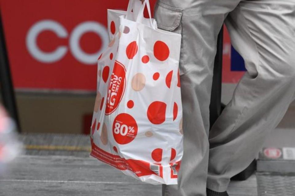 Coles shopping bag being carried by shopper exiting store