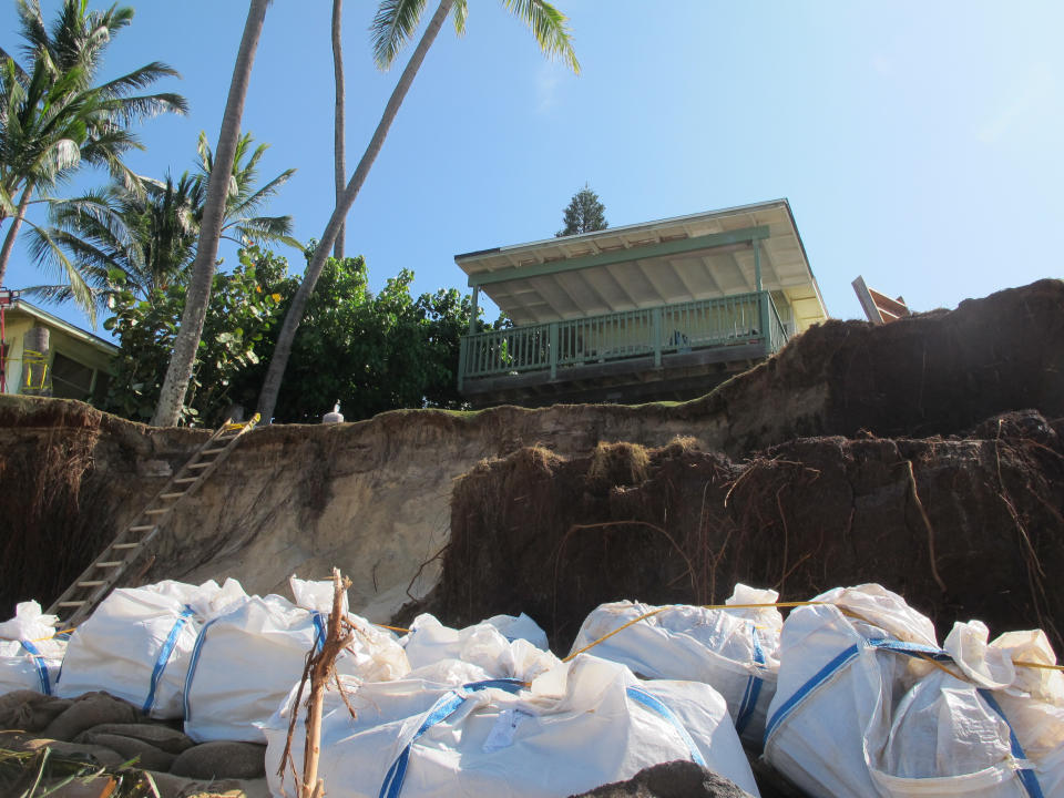 Sandbags are piled up in front of a house damaged by severe beach erosion in the Rocky Point neighborhood of Oahu's North Shore in Haleiwa, Hawaii on Tuesday, Dec. 31, 2013. Some property owners want to be able to install a seawall or something similar to protect their property, but scientists say doing so could lead the sand on the nearby coastline _ including Sunset Beach, home to some of the world’s top surfing contests _ to disappear. (AP Photo/Audrey McAvoy)