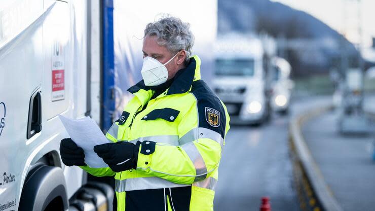 An der Grenze zwischen Bayern und Tirol kontrolliert ein Bundespolizist die Dokumente des aus Österreich kommenden Lkw-Fahrers. Foto: dpa