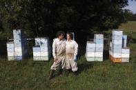 Beekeepers James Cook and Samantha Jones pose for a portrait in front of some of their hives at one of their bee yards near Iola, Wis., on Wednesday, Sept. 23, 2020. The couple has worked with honey bees for several years but started their own business this year — and proceeded with plans even after the coronavirus pandemic hit. (AP Photo/Carrie Antlfinger)