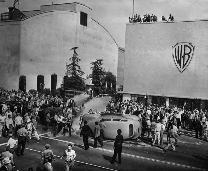 Oct. 5, 1945: Strikers outside of employee entrance to Warner Brothers Studios in Burbank. Strikers and non-strikers clashed in fights as non-strikers tried to cross picket line. Studio firemen, center, background, turn hose on battlers. Two workers' cars and officers' car, at the left, were overturned as they attempted to enter the studio. This photo appeared in the Oct. 6, 1945, Los Angeles Times.