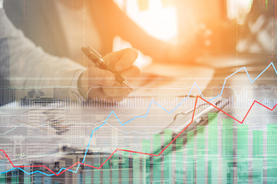 People making calculations with a stock chart in the foreground.