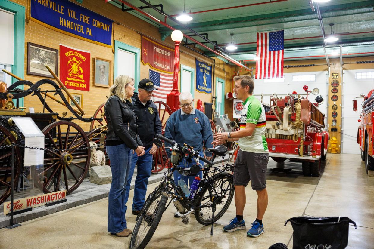 From left, Hanover Mayor SueAnn Whitman, Hanover Police Chief Chad Martin, and retired Hanover Fire Commissioner James Roth look at the bicycle of Andreas Beneke, from Hannover, Germany, as Beneke visits the Greater Hanover Area Fire Museum while on a bicycle trip around the world, Friday, April 19, 2024, in Hanover Borough.