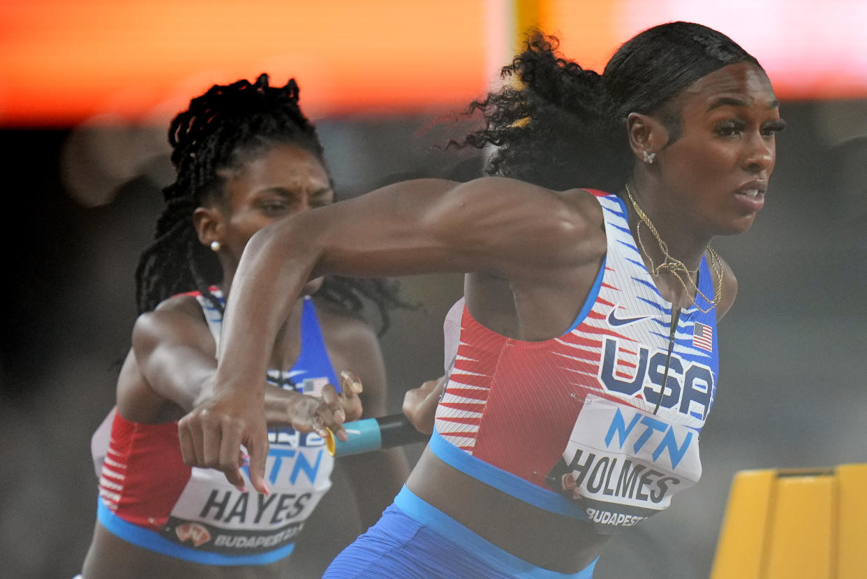 Alexis Holmes (right) receives the baton from Quanera Hayes, during the 4x400-meter relay heat at the World Athletics Championships in Budapest, Hungary, on Saturday. (AP Photo/Petr David Josek)