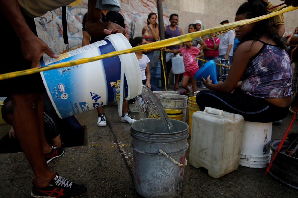 Varias personas hacen cola para recolectar agua de una tubería subterránea el 1 de abril en Caracas (Venezuela). (Foto: Carlos Garcia Rawlins / Reuters).