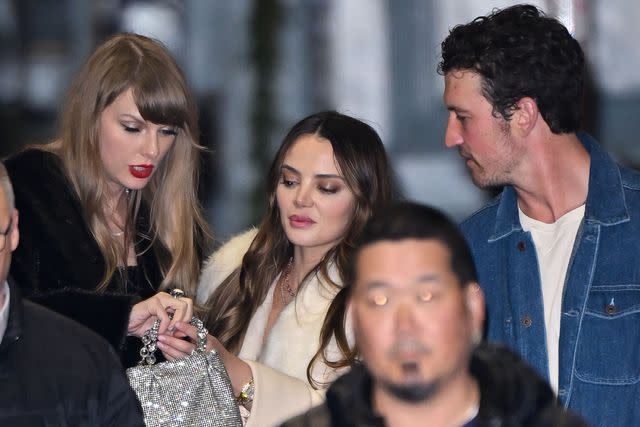 <p>James Devaney/GC Images</p> Taylor Swift shows off her new ring to friends Miles Teller and his wife Keleigh Sperry after her birthday party on Dec. 13