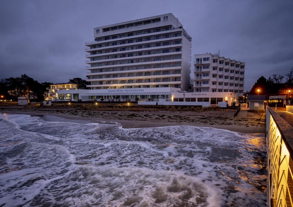 Waves land at the beach in Timmendorfer Strand at the Baltic Sea, Germany, Tuesday, Jan. 5, 2021. In background a five star hotel which is closed due to the Coronavirus. (AP Photo/Michael Probst)