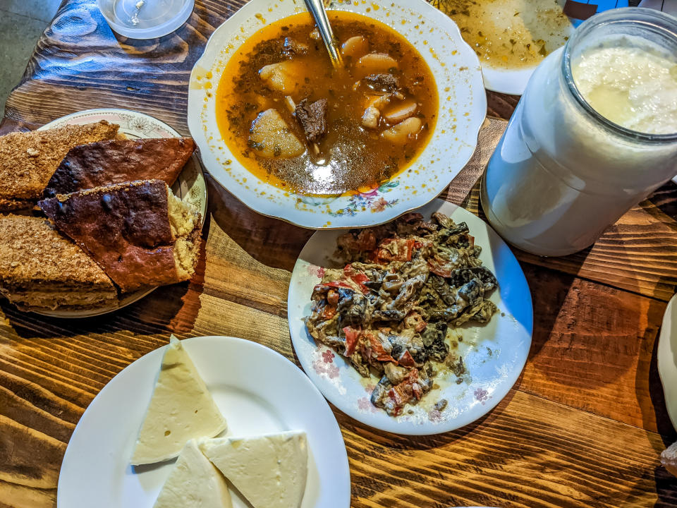 Assortment of traditional dishes with soup, bread, cheese and drink on a wooden table