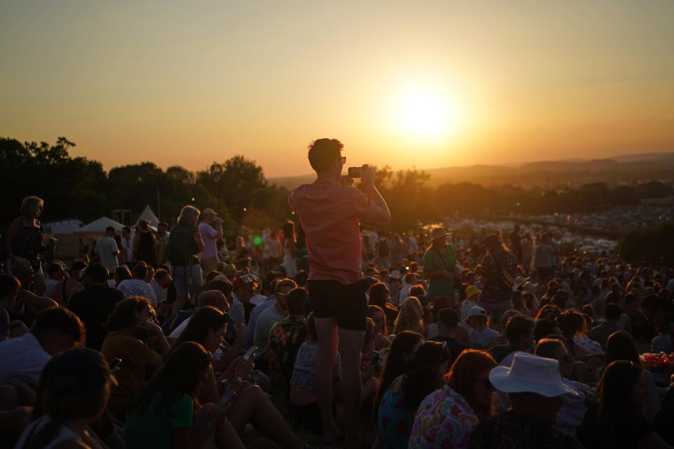 Festivalgoers watch the sunset (PA) (PA Wire)