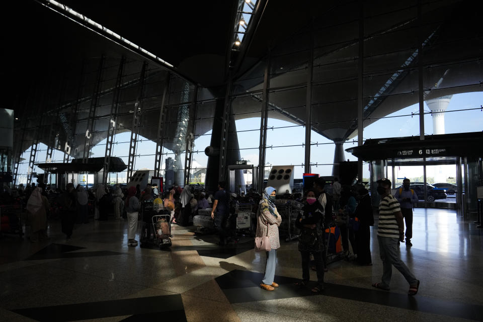 Travelers line up at check in counter at Kuala Lumpur International Airport in Sepang, Malaysia, Friday, April 1, 2022. Malaysia's international borders open to foreigners on Friday and fully vaccinated travelers do not have to undergo quarantine. (AP Photo/Vincent Thian)