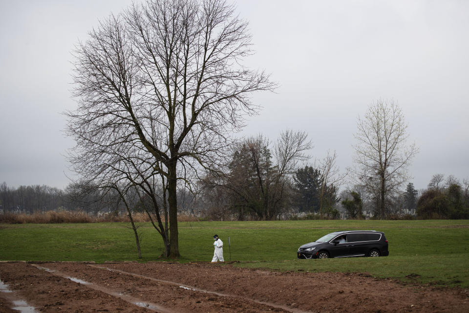 Rabbi Shmuel Plafker escorts Michael Tokar to the plot for the burial of his father, David Tokar, at Mount Richmond Cemetery in the Staten Island borough of New York, Wednesday, April 8, 2020. Between travel restrictions and potentially exposed family members kept in isolation, many funerals now have no mourners on site. When they do, they are prohibited from gathering at the graveside, instead listening to rushed services by phone from cars parked 50 feet away. (AP Photo/David Goldman)