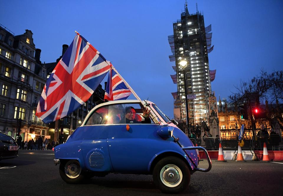 A man waves Union flags from a small car as he drives past Brexit supporters gathering in Parliament Square, near the Houses of Parliament