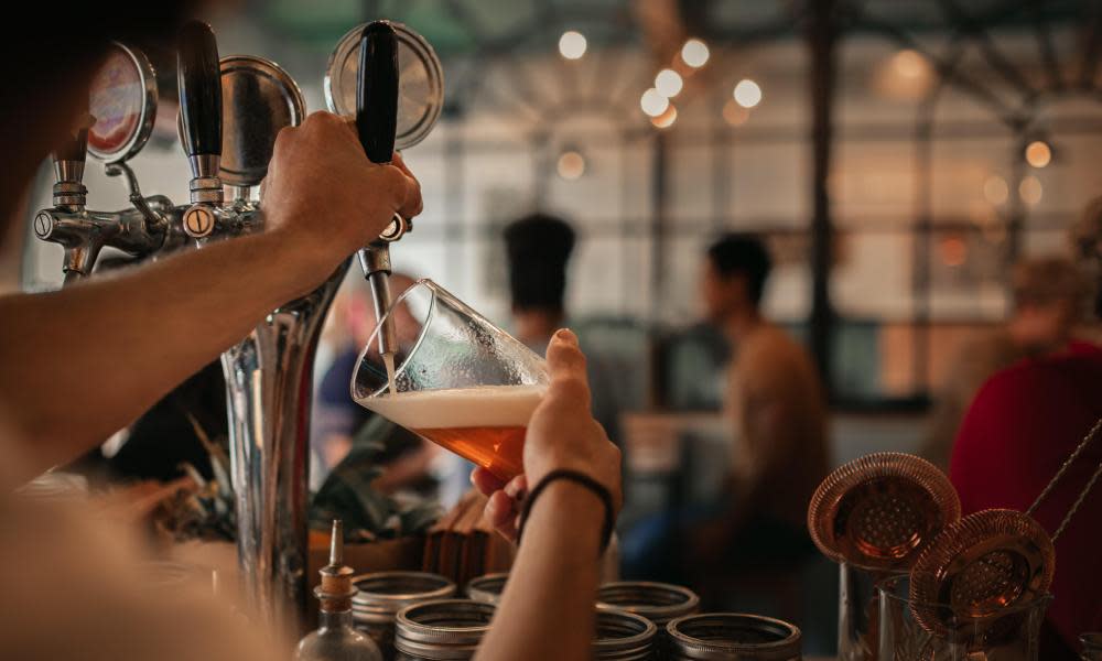 Bartender pouring beer behind a bar counter at night