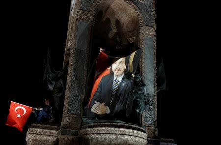 A supporter holds a banner with a photo of Turkish President Tayyip Erdogan, while standing on the Republic monument during a pro-government demonstration on Taksim square in Istanbul, Turkey, July 21, 2016. REUTERS/Alkis Konstantinidis