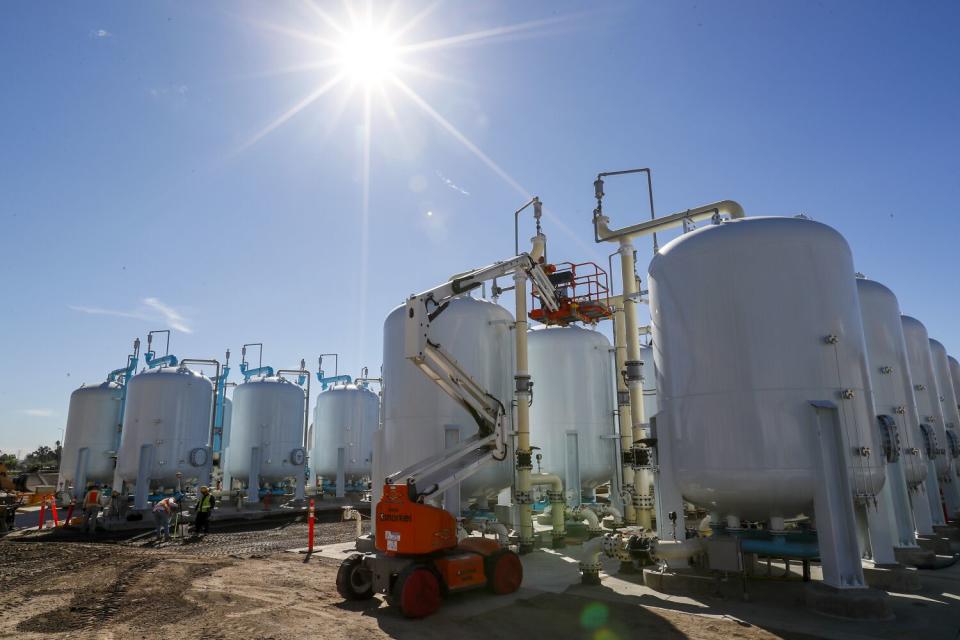 A group of above ground closed tanks standing on dirt outdoors.