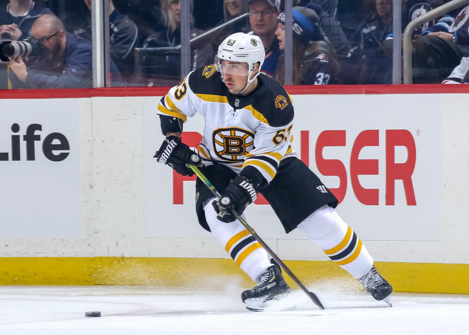 WINNIPEG, MB - MARCH 14: Brad Marchand #63 of the Boston Bruins plays the puck along the boards during first period action against the Winnipeg Jets at the Bell MTS Place on March 14, 2019 in Winnipeg, Manitoba, Canada. The Jets defeated the Bruins 4-3. (Photo by Jonathan Kozub/NHLI via Getty Images)