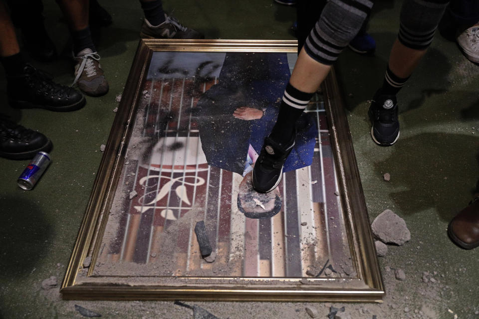 A protester steps on a damaged portrait of former legislative leader lie on the ground after protesters broke into the Legislative Council building in Hong Kong, Monday, July 1, 2019. Protesters in Hong Kong took over the legislature's main building Monday night, tearing down portraits of legislative leaders and spray painting pro-democracy slogans on the walls of the main chamber. (AP Photo/Vincent Yu)