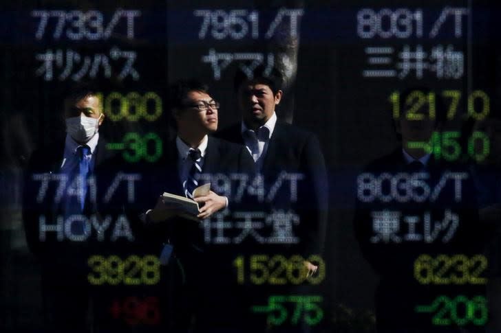 People are reflected in a display showing market indices outside a brokerage in Tokyo, Japan, February 10, 2016. REUTERS/Thomas Peter/File Photo - RTSPU1K