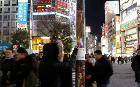 Japanese graffiti artist, known as 281 Antinuke, affixes his sticker art depicting U.S. President Donald Trump, on a lamppost in Tokyo's Shibuya shopping and entertainment district, Japan, January 27, 2017. REUTERS/Toru Hanai