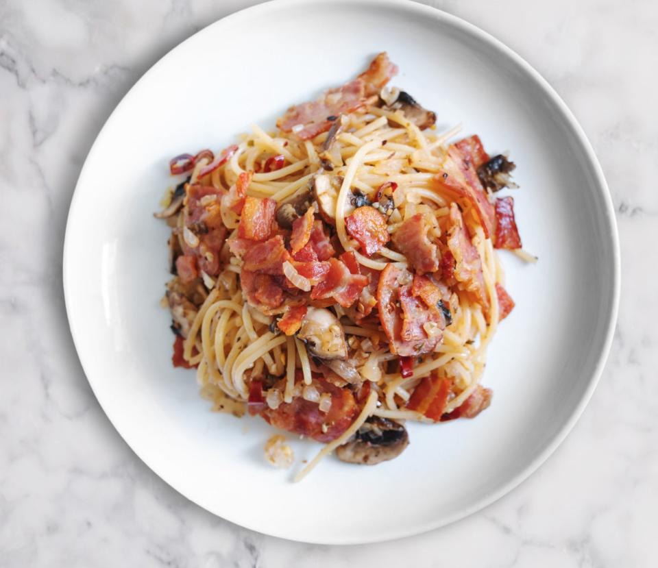 A plate of pasta with bacon and mushrooms