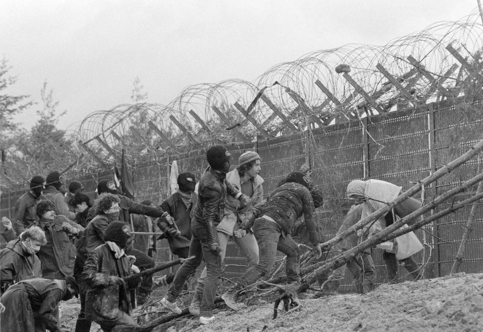 FILE - Protesters scale the fence of a construction site of a nuclear recycling power plant in Wackersdorf, West Germany, March 31, 1986. Germany is shutting down its last three nuclear power plants on Saturday, April 15, 2023, as part of an energy transition agreed by successive governments. The final countdown, delayed for several months over feared energy shortages because of the Ukraine war, is seen with relief by Germans who have campaigned against nuclear power. (AP Photo/Dieter Endlicher, File)