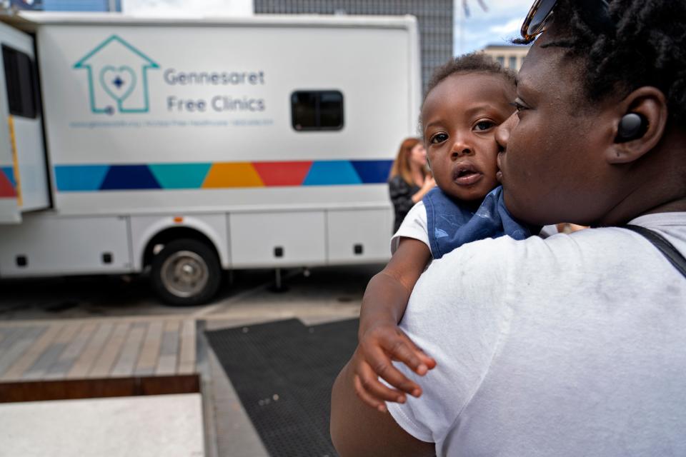 Tationa Sims holds her son, Noah Sims, as she waits for an appointment at the Gennesaret Free Clinic, Tuesday, May 17, 2022 on Washington St. outside the Julia M. Carson Transit Center. IndyGo has launched a pilot program, called "Wellness in Transit," providing the free mobile health clinic at the transit center operating Tuesdays in May through October. 