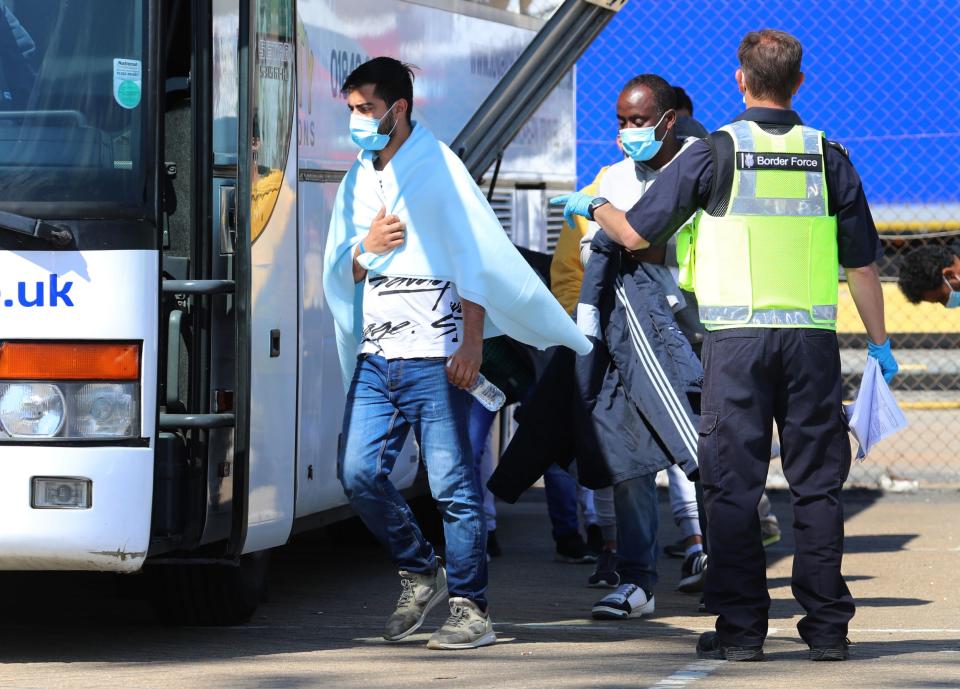 Men thought to be migrants boarding a bus (PA)