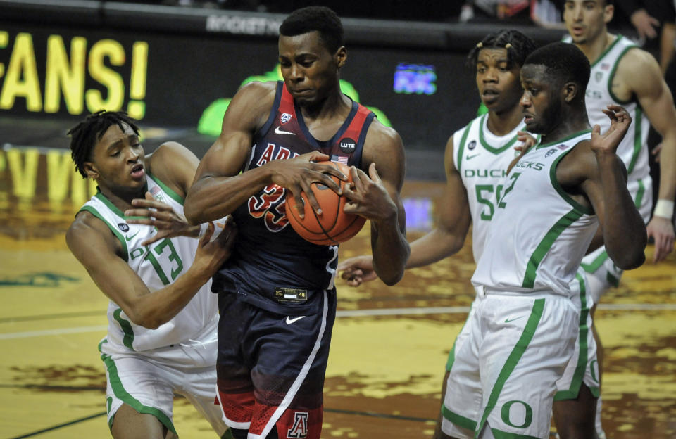 Arizona center Christian Koloko (35) secures the ball as he is defensed by Oregon forwards Chandler Lawson (13), Eric Williams Jr. (50) and Eugene Omoruyi (2) during the first half of an NCAA college basketball game Monday, March 1, 2021, in Eugene, Ore. (AP Photo/Andy Nelson)