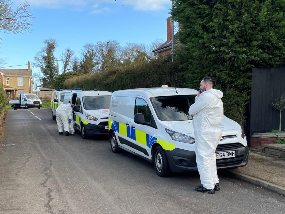 Police forensics officers at the scene in The Row in Sutton, near Ely (PA)