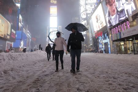 People walk in the middle of 7th Avenue during a snow storm in Times Square in the Manhattan borough of New York, January 23, 2016. REUTERS/Carlo Allegri