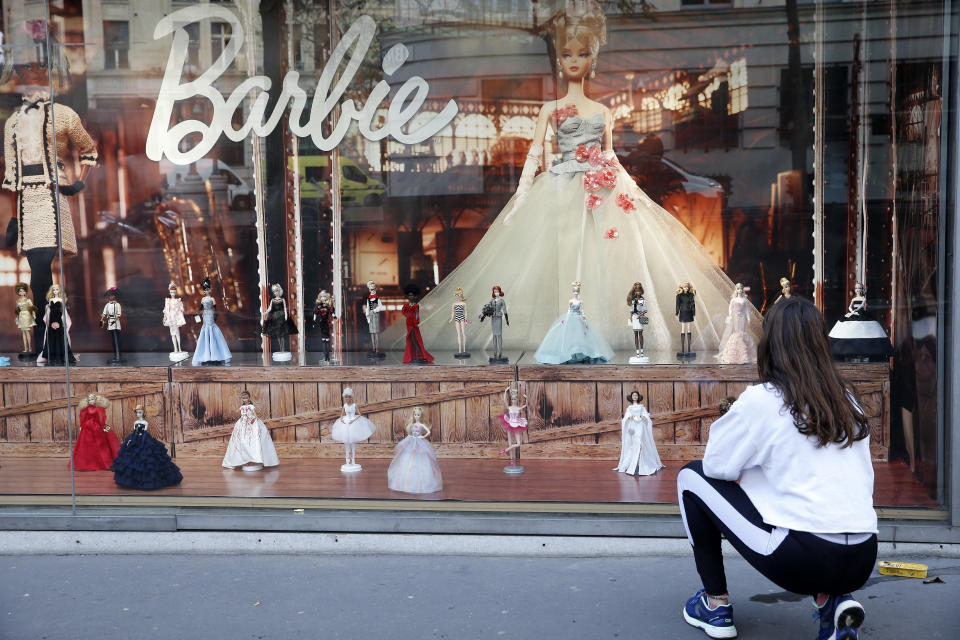 PARIS, FRANCE - DECEMBER 01: A woman wearing a protective face mask looks at various Barbie dolls on display in the window of a toy store for Christmas on December 01, 2020 in Paris, France. The reopening of stores selling 