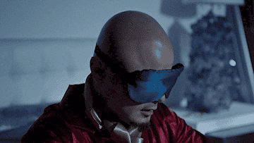 A man posing as pitbull removes a sleep mask to reveal a pair of sunglasses
