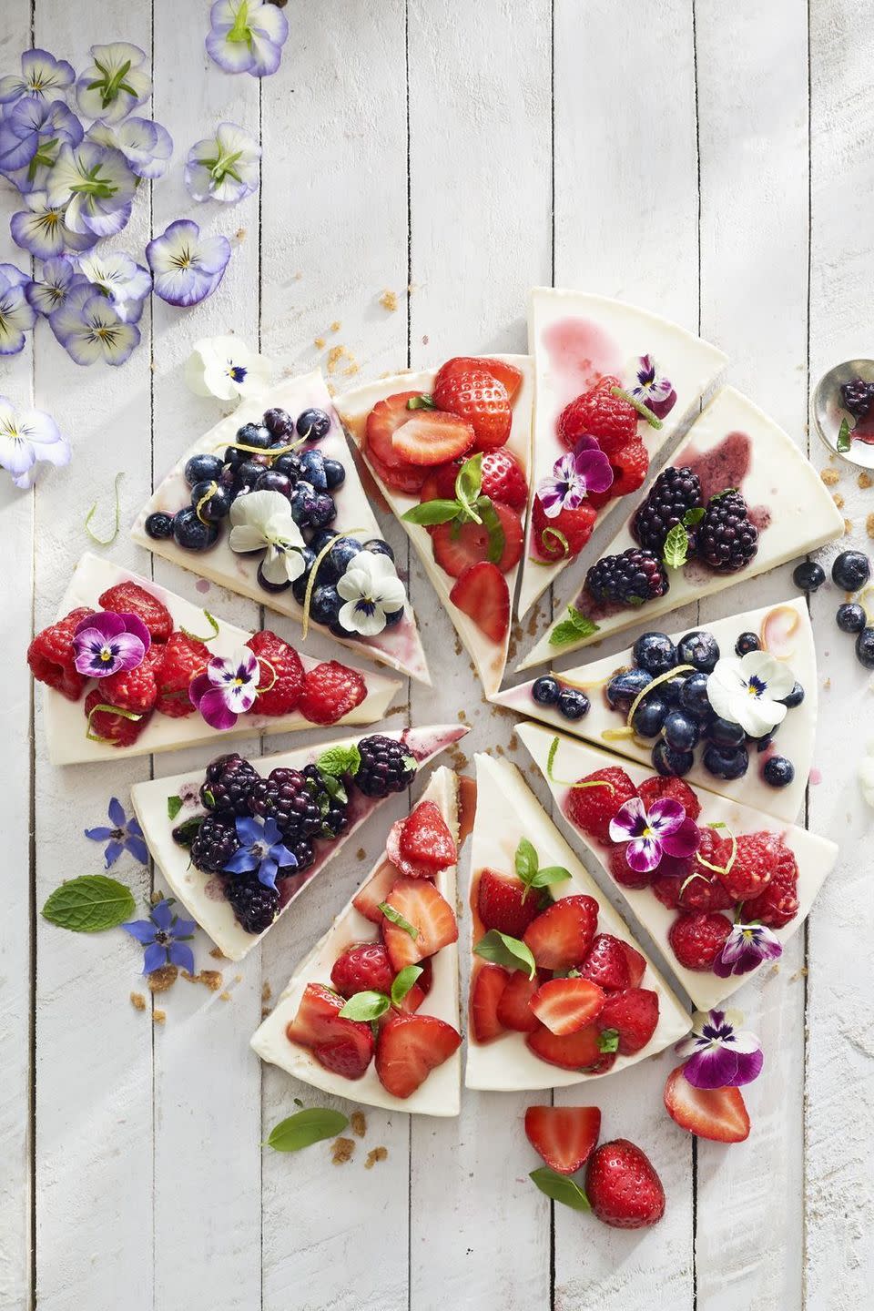 no bake cheesecake cut into slices with various berry toppings on each slice