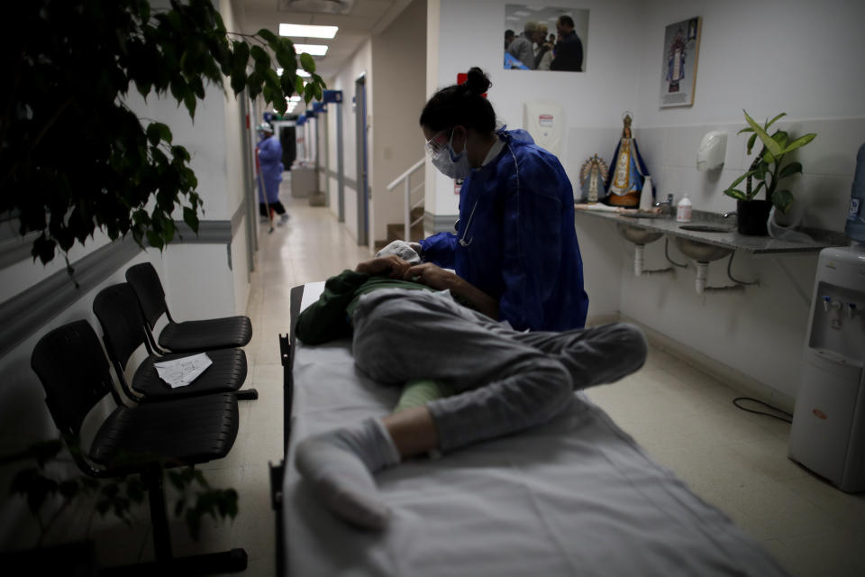 Dr. Veronica Verdino touches a non-COVID-19 patient who is waiting for a tomography at Llavallol Dr. Norberto Raúl Piacentini Hospital in Lomas de Zamora, Argentina, Saturday, May 8, 2021. "We're cutting corners everywhere ... We have all the illnesses other than COVID, plus this (coronavirus) wave that exploded," Verdino said during a recent 24-hour shift. (AP Photo/Natacha Pisarenko)