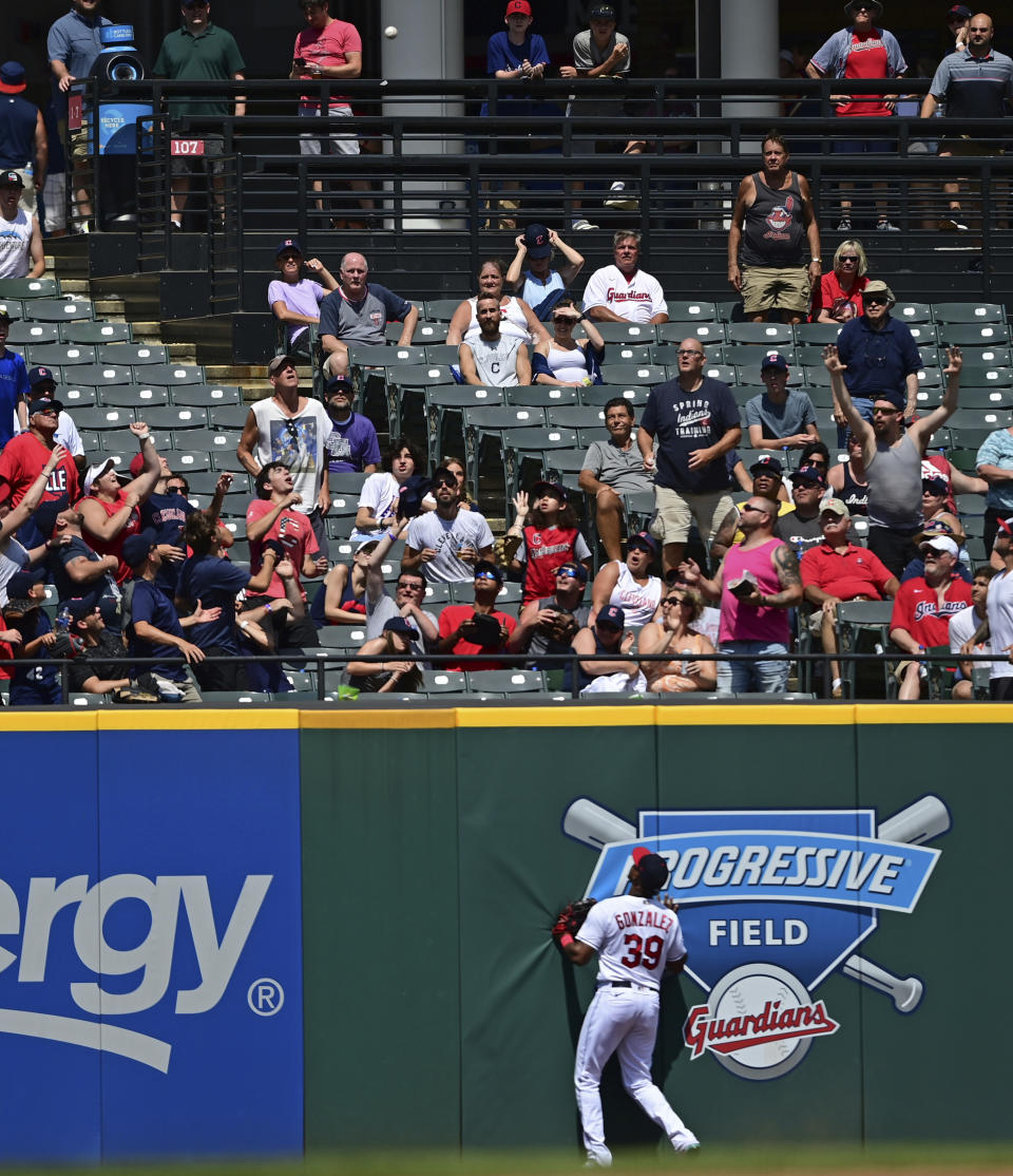 Fans reach for Arizona Diamondbacks' Alek Thomas two-run home run ball as Cleveland Guardians right fielder Oscar Gonzalez watches during the sixth inning of a baseball game, Wednesday Aug. 3, 2022, in Cleveland. (AP Photo/David Dermer)