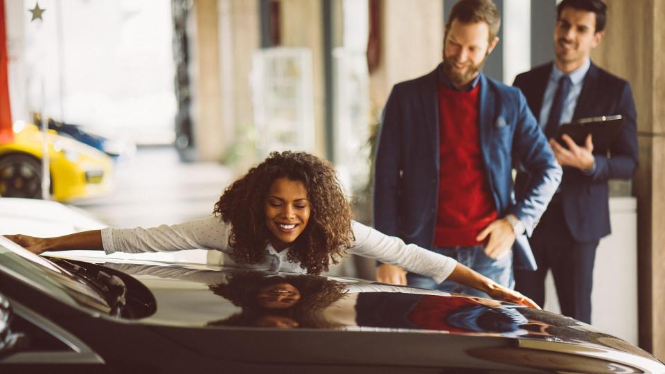 Young woman and her husband in the showroom purchasing new car.