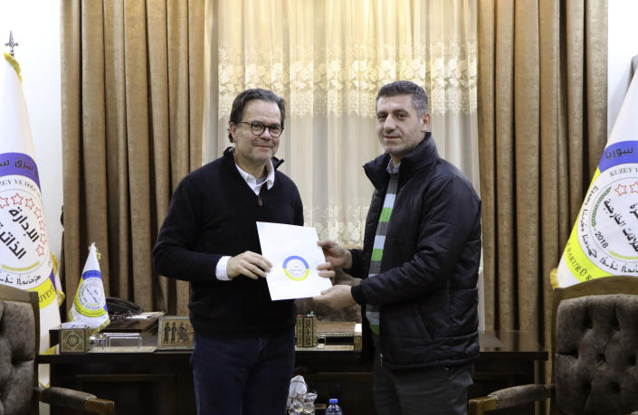 In this photo provided by Autonomous Administration of North and East Syria, Stéphane Romatet, head of the crisis management and support center in the French Foreign Ministry, left, poses for a photo with Robel Baho, Deputy Head of the External Relations Department of the Autonomous Administration of North and East Syria, after signing a document of surrender for women and children of Islamic State group militants, at the department's headquarters in the city of Qamishli, Syria, Monday, Jan. 23, 2023. France has repatriated another group of women and children from former Islamic State group-controlled areas of Syria. (Autonomous Administration of North and East Syria via AP)