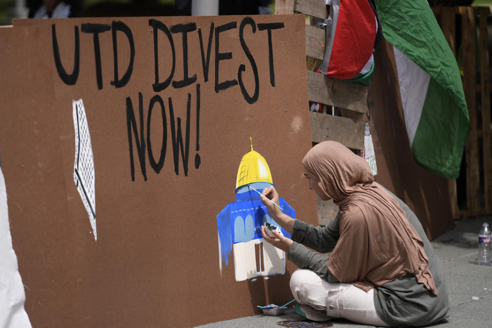 A woman paints on a barrier during a protest set up in a plaza at the University of Texas at Dallas, Wednesday, May 1, 2024, in Richardson, Texas. (AP Photo/LM Otero)