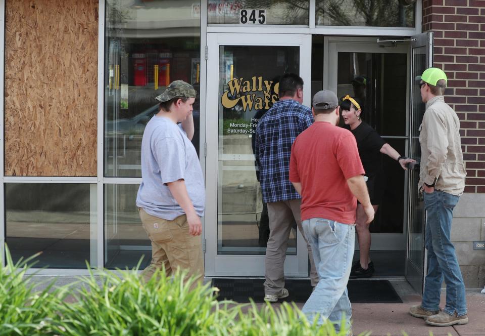 A worker at Wally Waffle lets patrons know they are open after the windows in the restaurant were broken during evening disturbances in Highland Square in Akron on Thursday. It's unclear if the unrest in the area was related to Jayland Walker protests.